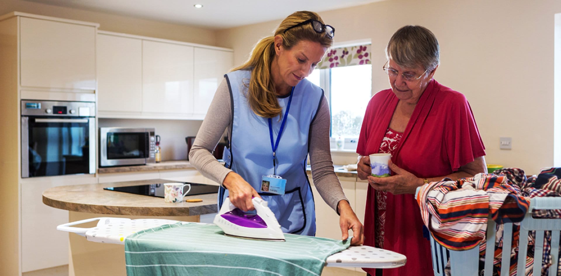 caregiver ironing clothes with senior woman